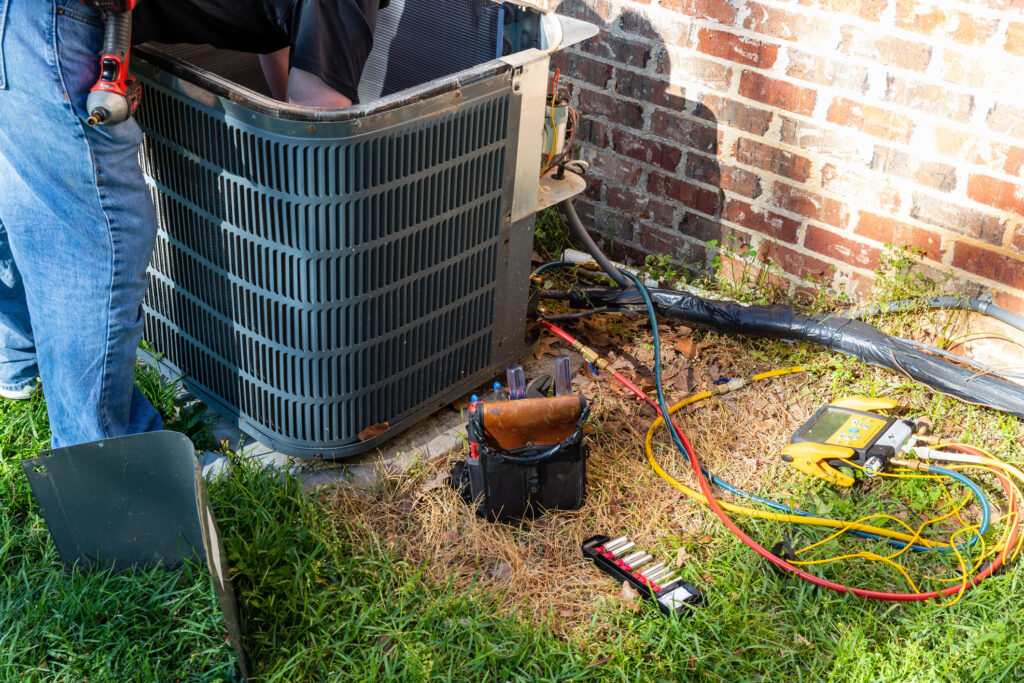 HVAC technician repairing an outdoor air conditioning unit.
